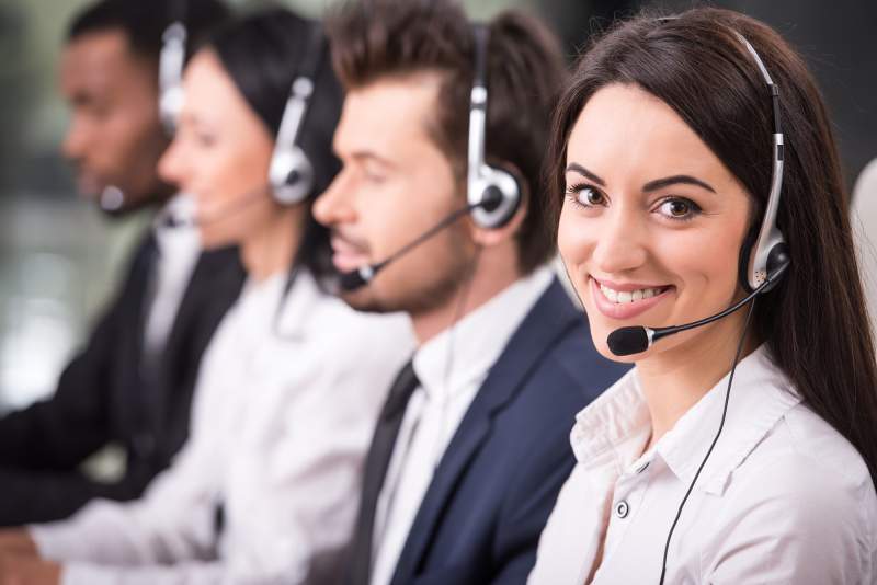 Two men and two women in a row, with a headset, smiling